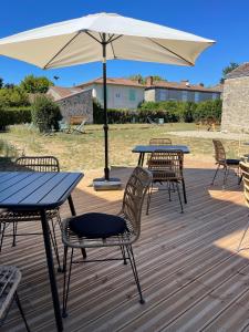 une table et des chaises avec un parasol sur une terrasse dans l'établissement Hôtel de la Glane, à Oradour-sur-Glane