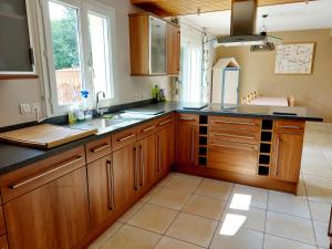 a kitchen with wooden cabinets and a large window at Chambres d'hôtes chez l'habitant - Bed & Breakfast homestay in Huisnes-sur-Mer