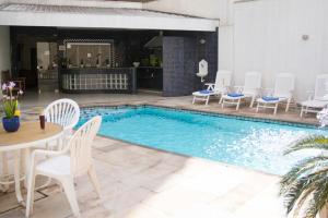 una piscina con sillas blancas, mesa, mesa y sillas en Mariano Palace Hotel, en Campinas