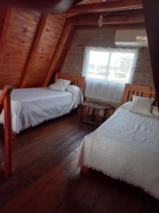 Habitación con 2 camas y ventana en una cabaña en Los Lirios en Sierra de la Ventana