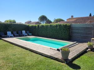 una piscina en un patio con terraza de madera en Villa de la Capèra, en Camaret-sur-Aigues