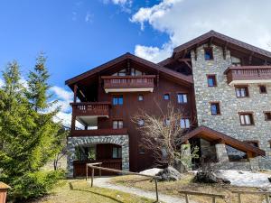 - un grand bâtiment en bois avec un balcon dans l'établissement SkiMottaret, à Méribel