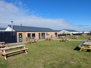 a group of picnic tables in the grass in front of a building at Beachside Lighthouse 14 in Lossiemouth