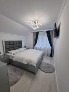 - une chambre avec un grand lit et un lustre dans l'établissement Căsuța dintre brazi, à Râșnov