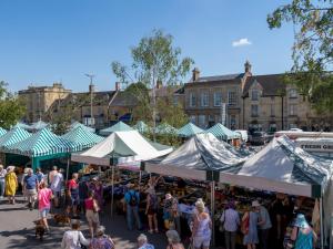 a group of people walking around a market with tents at Pass the Keys Elegant stylish home in historic town centre sleeps 3 in Moreton in Marsh