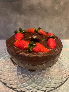 a chocolate cake with strawberries on a glass plate at Pousada Luar do Prata in Trindade