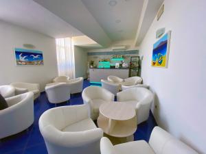 una sala d'attesa con sedie bianche e un tavolo di Hotel Stella Maris Terme a Ischia