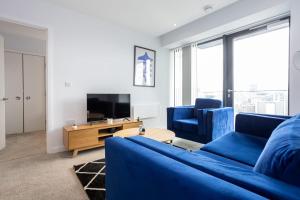 ein Wohnzimmer mit einem blauen Sofa und einem TV in der Unterkunft Stunning 2 Bedroom Apartment Manchester in Manchester