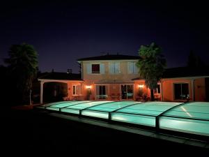 a large swimming pool in front of a house at night at Charmant logis neuf équipé/Piscine/SPA/Sauna/Gym 