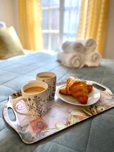 uma bandeja com duas chávenas de café e croissants numa cama em Cute and cosy studio in a Fantastic Location! BISHOPS STORTFORD em Bishop's Stortford