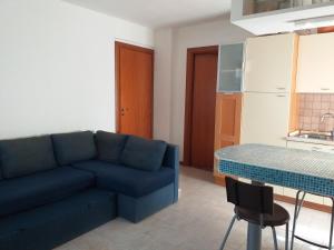 a living room with a blue couch and a kitchen at Camerota Basic Appartamenti in Lentiscosa