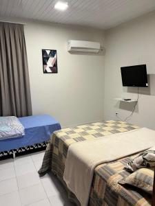 a hotel room with two beds and a tv at Casa em ótima localização in Boa Vista