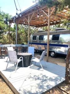 d'une terrasse avec des chaises, une table et une camionnette. dans l'établissement The Steel Magnolia Airstream - Cabins At Rim Rock, à Austin