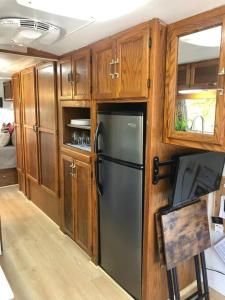 a kitchen with a black refrigerator and wooden cabinets at The Steel Magnolia Airstream - Cabins At Rim Rock in Austin