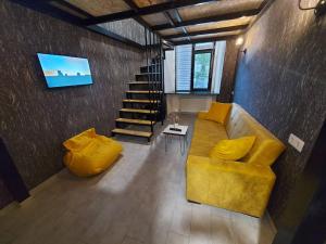 a living room with a yellow couch and stairs at The Passenger Rooms in Tbilisi City