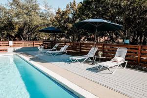 un grupo de sillas y sombrillas junto a una piscina en The Steel Magnolia Airstream - Cabins At Rim Rock en Austin