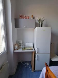 eine kleine Küche mit einem weißen Kühlschrank und einem Tisch in der Unterkunft Bureau Lesparre-médoc, l'estuaire in Lesparre-Médoc