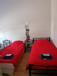 2 Betten in einem Zimmer mit roter Bettwäsche in der Unterkunft Bureau Lesparre-médoc, l'estuaire in Lesparre-Médoc