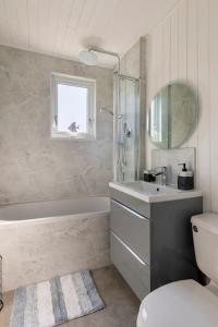uma casa de banho com uma banheira, um lavatório e um WC. em Luxury Family Beachside Home inc Hot Tub & Parking em Broad Haven