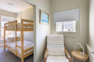 a bunk bed in a small room with a chair at Luxury Family Beachside Home inc Hot Tub & Parking in Broad Haven