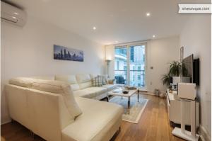 a white living room with a couch and a table at Veeve - Modernist Wharf in London