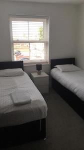 a bedroom with two beds and a window and a night stand at Captivating 2-Bed Apartment in Brentwood in Brentwood