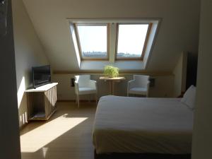 a bedroom with a bed and a table and two windows at b&b Kraaiberg in Heuvelland