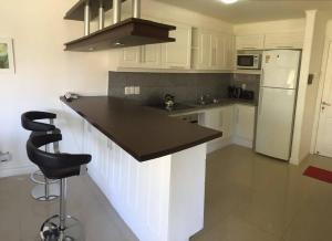 een keuken met witte kasten en een zwart aanrecht bij Green Park Hermosos Apartamentos Vista al Lago in Punta del Este
