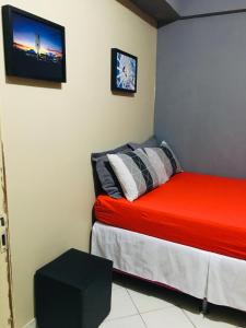 - une chambre avec un lit rouge et une télévision murale dans l'établissement Apartamento para temporada perto do aeroporto de Brasilia, à Brasilia
