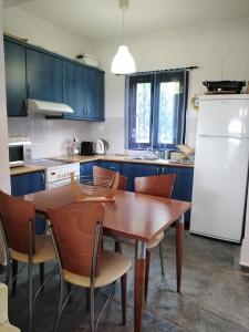 uma cozinha com uma mesa e cadeiras e um frigorífico branco em Rebekka's Guest House Elani em Siviri