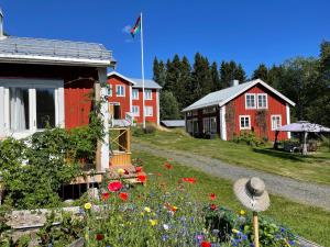 um grupo de casas com flores num quintal em Pelle Åbergsgården em Nordingrå