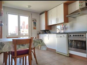 una cocina con armarios blancos y una mesa con sillas. en Apartamento EntreRíos, en Barbastro