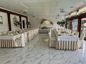 a row of tables in a banquet hall with white table settings at Hotel Adria in Ruda Śląska