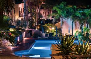 una piscina con palmeras y un escenario en Villaggio Cala Mancina en San Vito lo Capo
