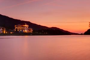 a building on the shore of a lake at sunset at Satorikan in Gosen