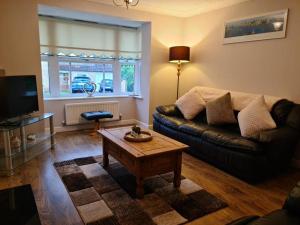 a living room with a couch and a coffee table at Spacious 4 bed home in a quiet cul-de-sac in Coundon