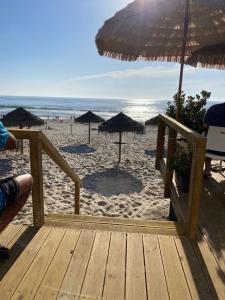 un sentiero in legno per la spiaggia con ombrelloni e l'oceano di Pé n'areia a Praia de Mira