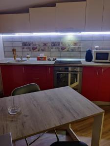 une cuisine avec des placards rouges et une table en bois dans l'établissement Zen Studio Slatina, à Slatina