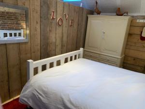 a bedroom with a white bed and a wooden wall at Quirky Barn Conversion Crowhurst Battle in Crowhurst