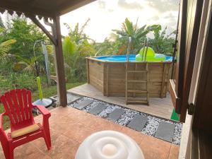 um pátio com uma banheira de hidromassagem e uma cadeira vermelha em Magnifique Lodge en bois avec piscine et jardin de 800 m2 em Le Lamentin