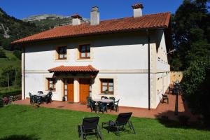 a white house with tables and chairs in a yard at Apartamentos Rurales la Taberna in Matienzo