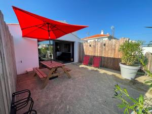 un patio con una mesa de picnic y una sombrilla roja en NOIRMOUTIER - Petite maison 500m plage Sableaux en Noirmoutier-en-l'lle
