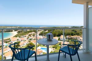a balcony with a table and chairs and the ocean at Palladium Hotel Menorca in Arenal d'en Castell