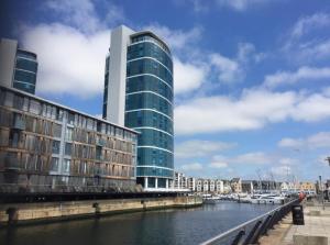 a tall glass building next to a river with boats at Luxury 8th Floor Apartment with Stunning Views in Chatham