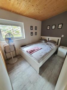 a bedroom with a bed and a window and a fan at Orfűi Kisház in Orfű