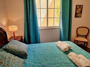 a bedroom with a bed with blue curtains and a window at Tavira City Center 3Br in Tavira