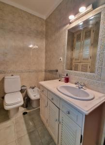 a bathroom with a sink and a toilet and a mirror at Tavira City Center 3Br in Tavira