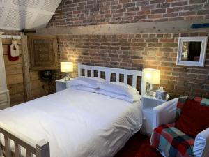 a bedroom with a white bed and a brick wall at Quirky Barn Conversion Crowhurst Battle in Crowhurst