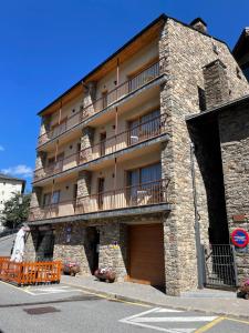 a large stone building with a balcony on it at Apartaments Casa Vella Popaire in Soldeu