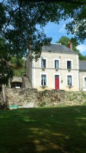 un edificio con una puerta roja en una pared de piedra en La Maison des Renaudières, en Azay-le-Rideau
